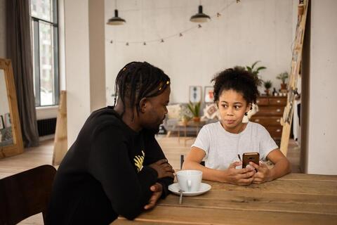 Picture of black father talking to daughter using smartphone.