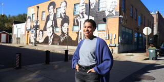 A Facing History alumni stands in front of the Memphis Upsdanders Mural.