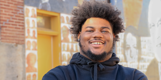 A Facing History alum smiles at the camera while standing in front of a mural in Memphis, TN.