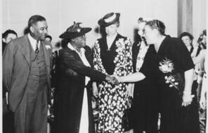 Two African American women shake hands in front of Eleanor Roosevelt.