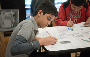 Students writing on a paper. 