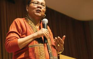 bell hooks standing on stage and speaking while holding a microphone. 