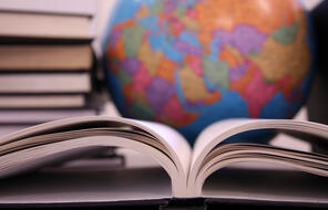 A side view of an open book with a colorful globe behind it