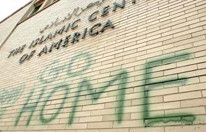 The words Go Home spray painted in green on a brick wall at the Islamic Center of America 