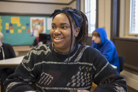 High school student sitting in classroom and smiling