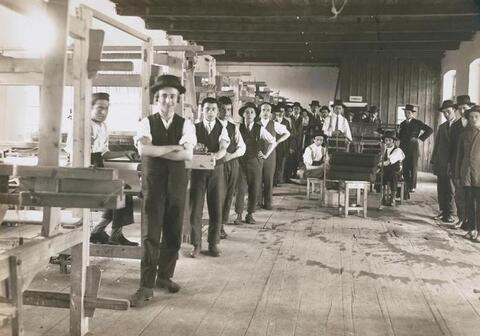 Boys standing beside weaving machines posing for a photo.