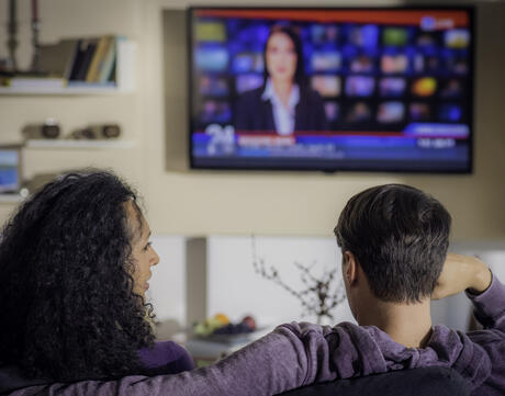 Photo of Two People Watching the News on TV