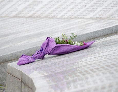Bouquet of flowers wrapped in purple fabric placed on monument.