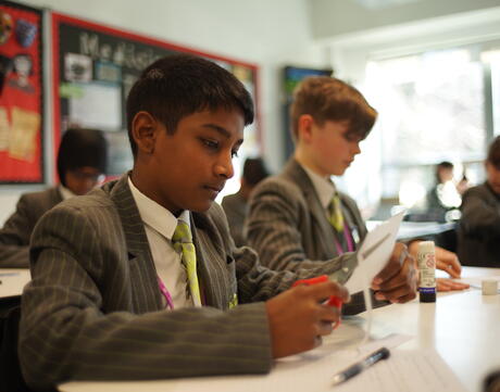 A student cuts a sheet of paper in a classroom at Skinners' Academy in Londonn