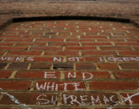 Chalk on bricks on the sidewalk that says "End White Supremacy"